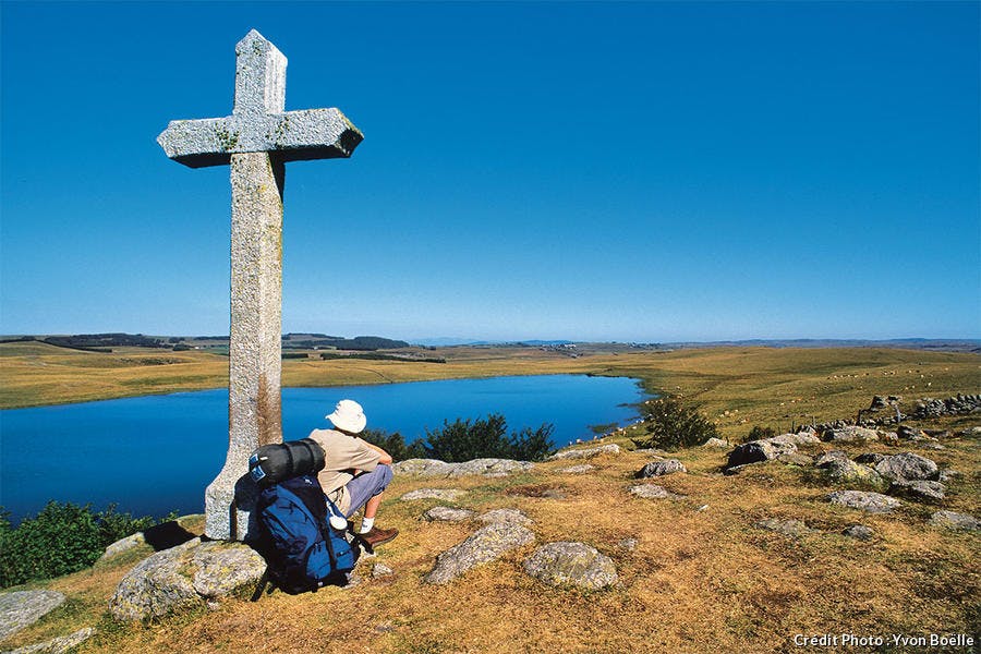 Un pélerin assis sous une croix 